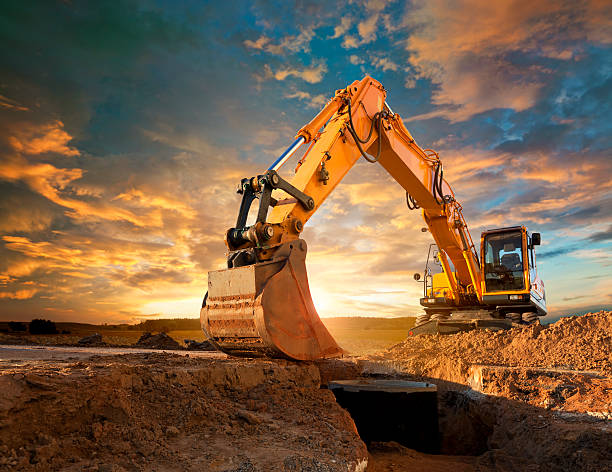 Excavator working an open mine face at sunset